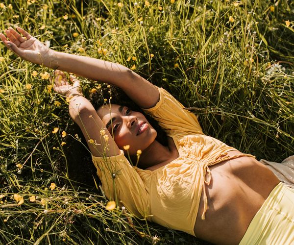 Happy person with arms outstretched towards the sun in a field.