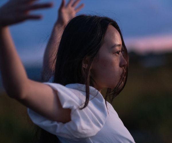 Person stretching gently outdoors with a serene landscape background.